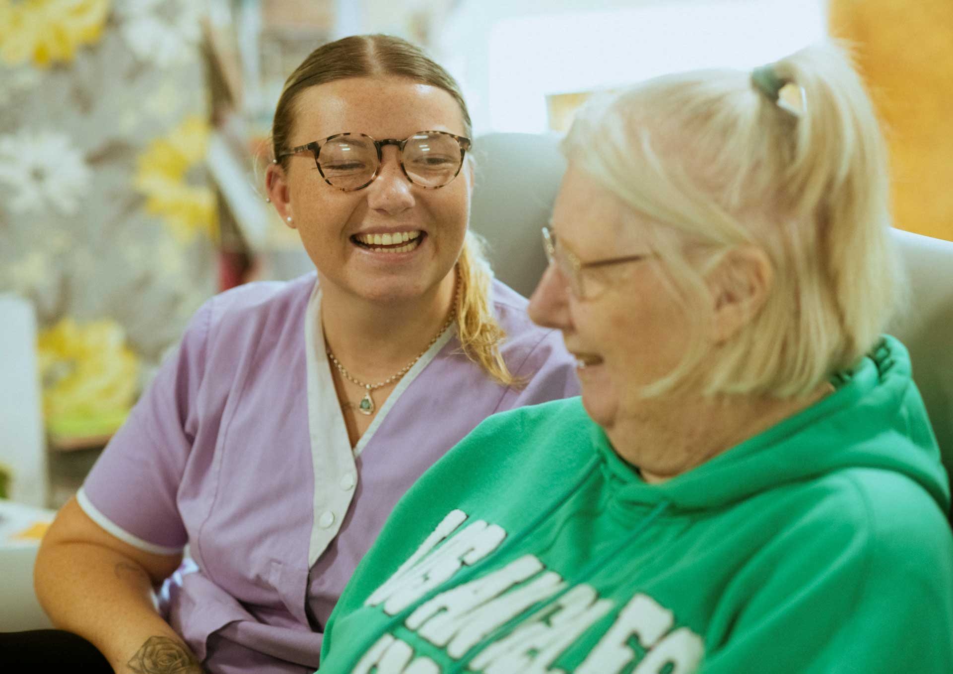 Young and elderly women sitting and smiling with one another.