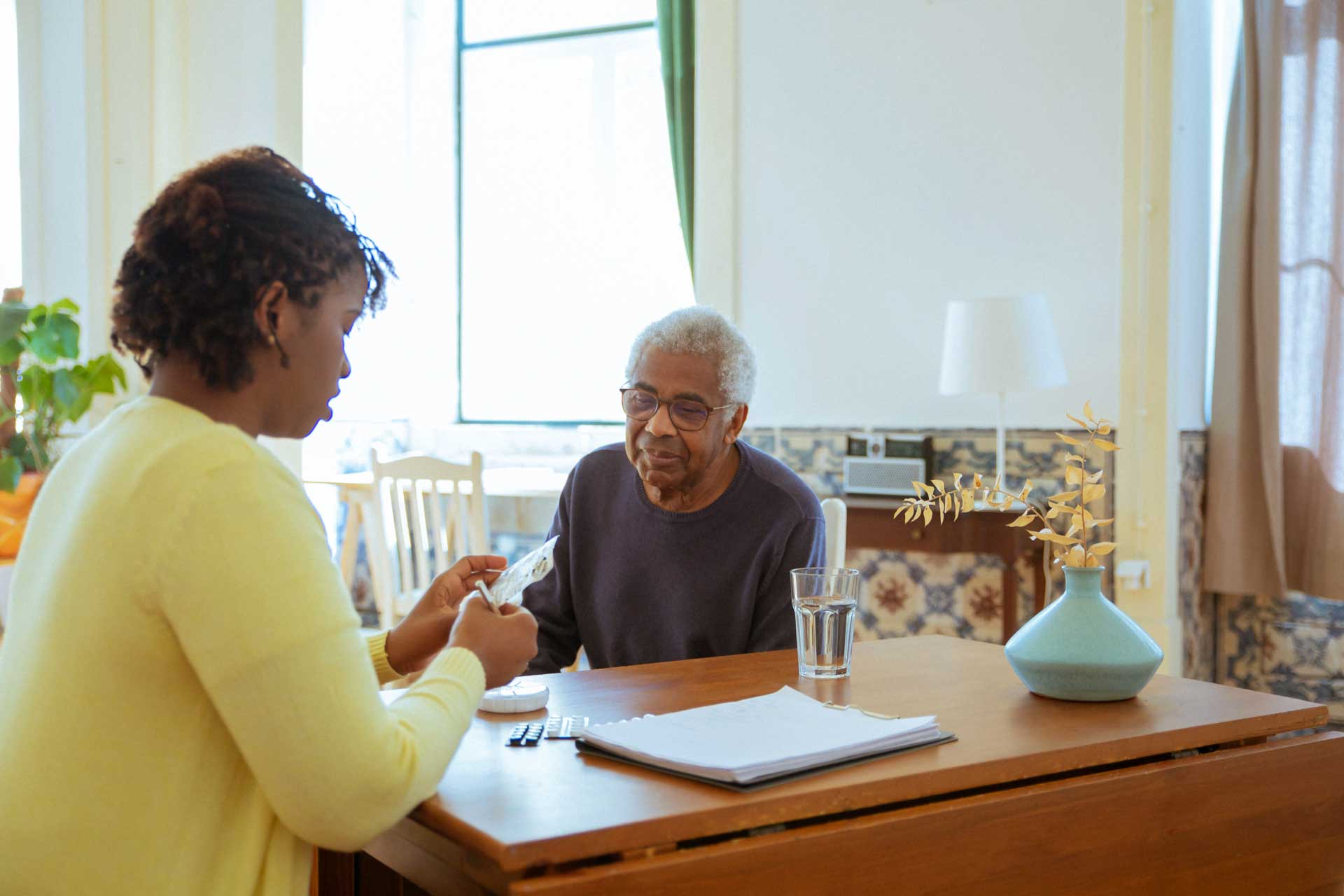 Young woman helping elderly man with medication.